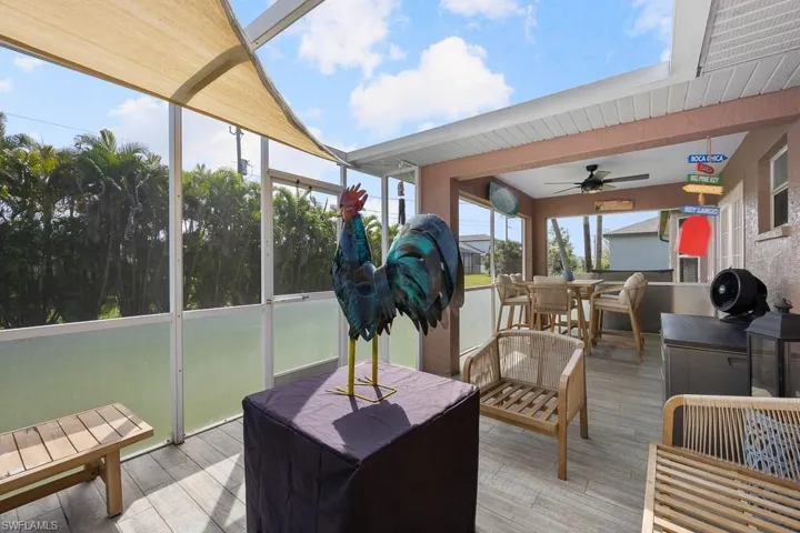 Tiled lanai featuring a sunroom, a ceiling fan, outdoor dining space, and area for grilling