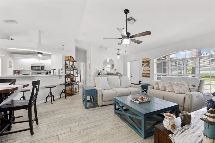 Living area featuring ceiling fan, vaulted ceiling, and light wood-style ceramic tile flooring