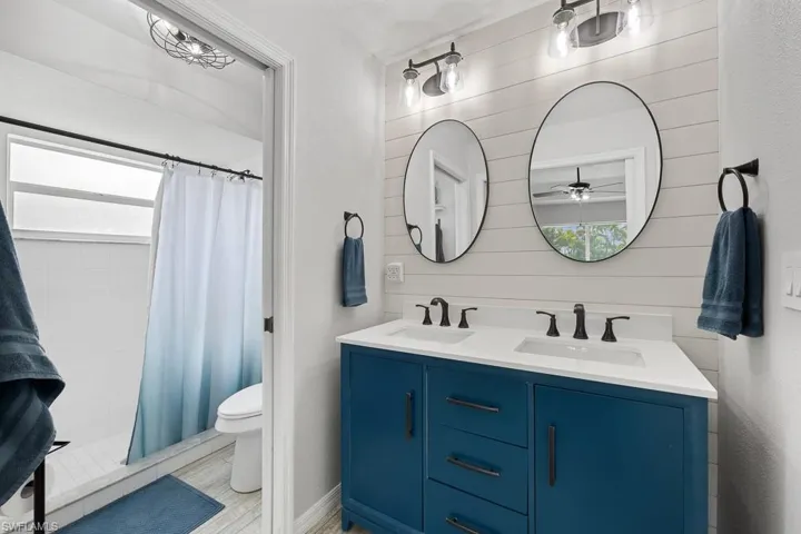 Bathroom featuring double vanity, a stall shower, and a ceiling fan