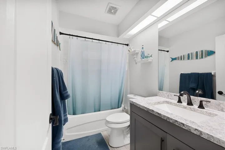 Bathroom featuring shower / bath combination with curtain and vanity