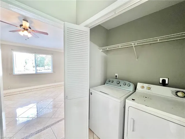 Washroom with ceiling fan, crown molding, washer and dryer, light tile flooring, and hookup for an electric dryer
