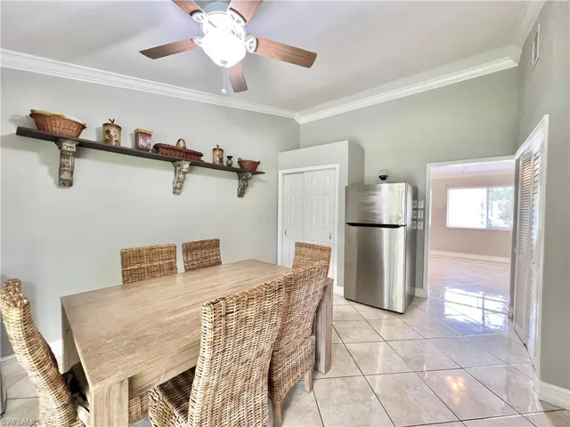 Tiled dining room with ceiling fan and ornamental molding