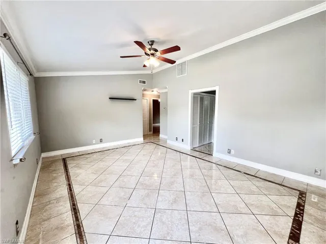 Spare room with ceiling fan, crown molding, and light tile floors