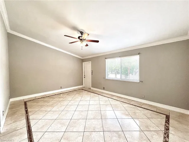 Unfurnished room with ornamental molding, ceiling fan, and light tile floors