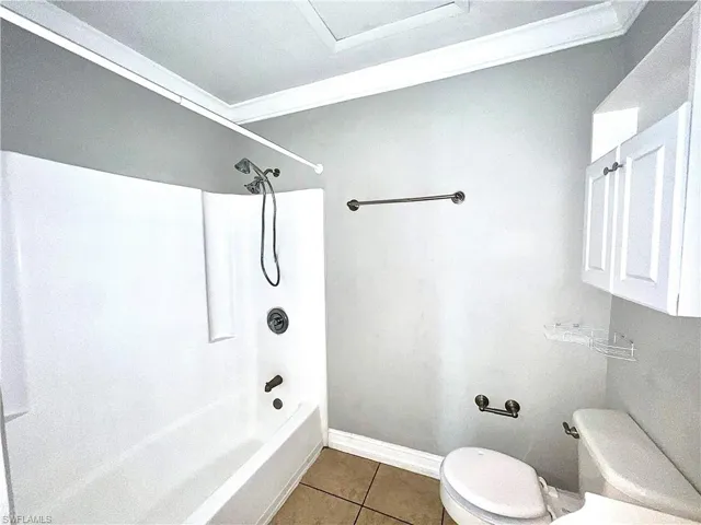 Bathroom with shower / bathtub combination, tile flooring, and toilet
