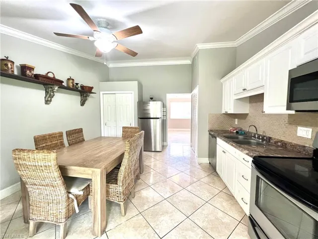 Kitchen featuring stainless steel appliances, backsplash, crown molding, white cabinetry, and sink