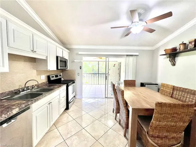 Kitchen with ceiling fan, ornamental molding, white cabinets, sink, and appliances with stainless steel finishes