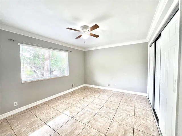 Tiled spare room featuring crown molding and ceiling fan