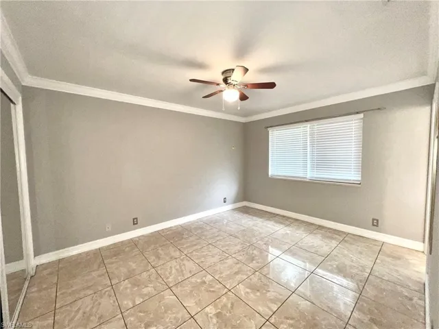 Spare room with ornamental molding, ceiling fan, and light tile flooring