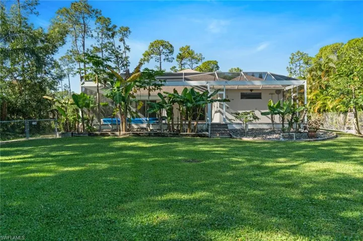 Rear view of house featuring a fenced backyard, fruit trees and garden
