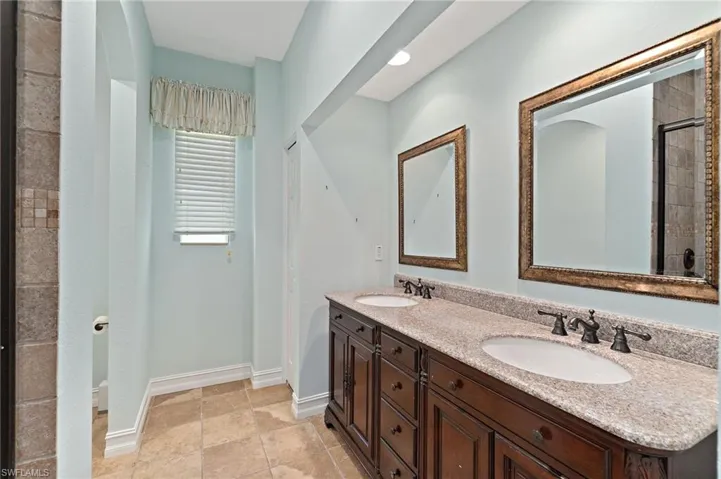 Full bathroom with double vanity and baseboards