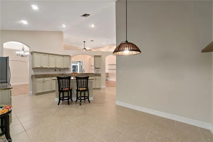 Kitchen with arched walkways, a kitchen breakfast bar, pendant lighting, refrigerator, and recessed lighting