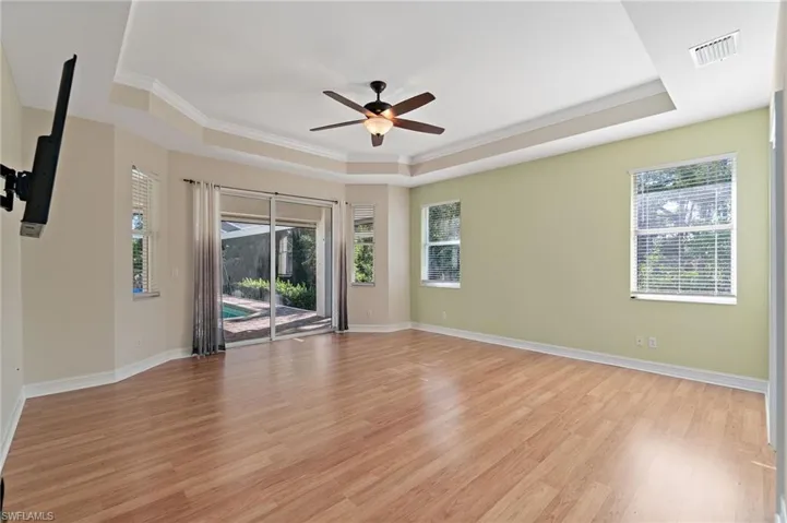 Unfurnished Main Bedroom featuring crown molding, light wood-style flooring, ceiling fan, ensuite bath & tray ceiling