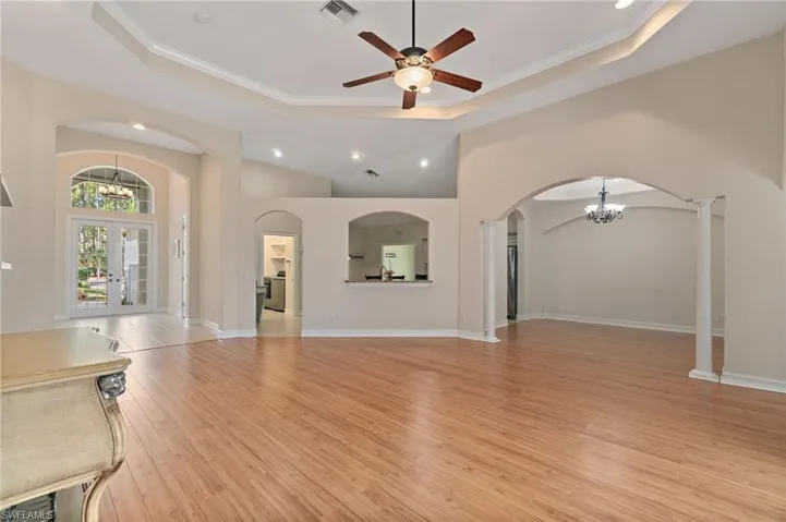 Unfurnished living room with a arched walkways, french doors, light wood finished floors, and crown molding