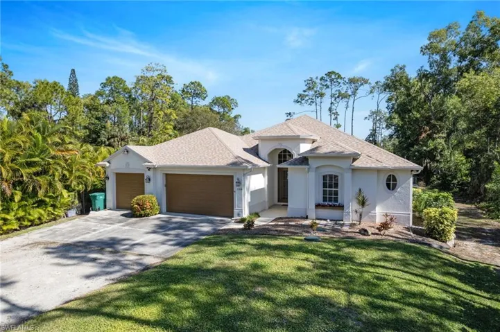 View of front facade featuring a shingled roof, an attached garage, stucco siding, and concrete pad