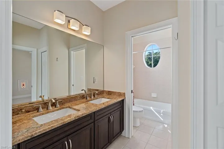 Bathroom featuring double vanity, light tile patterned floors, and shower / tub combination