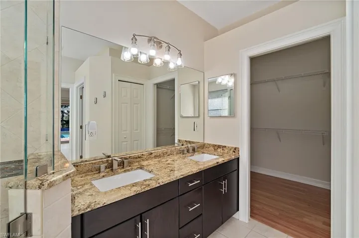 Main Bathroom featuring a spacious closet, double vanity, light tile patterned floors, and a stall shower