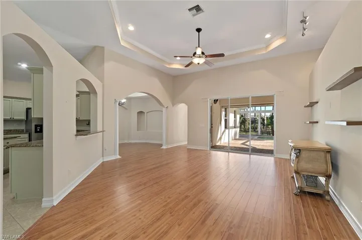 Unfurnished living room with arched walkways, light wood-style floors, a ceiling fan, ornamental molding, and recessed lighting