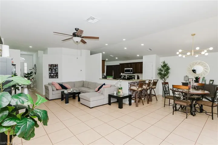 Living room with ceiling fan, suspended lighting, and light tile patterned floors