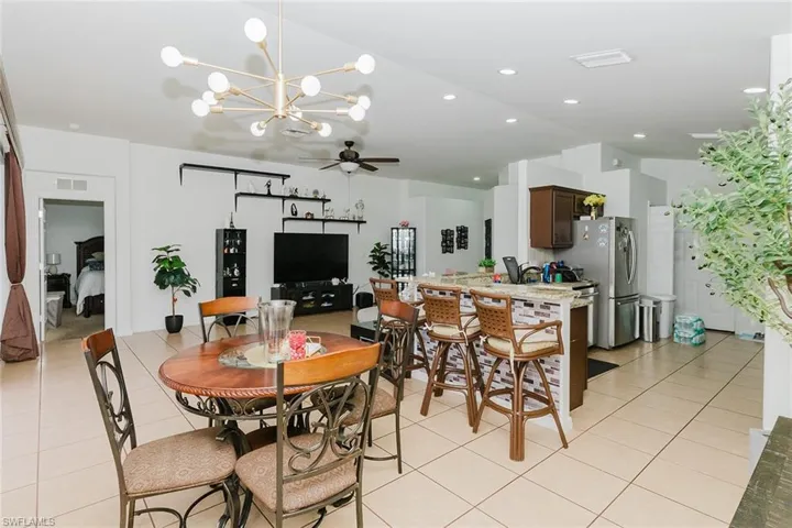 Dining area with hanging lights, ceiling fan, vaulted ceiling, and light tile patterned floors