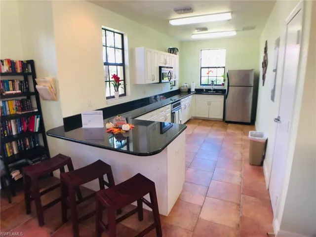 Kitchen with white cabinets, appliances with stainless steel finishes, plenty of natural light, and kitchen peninsula