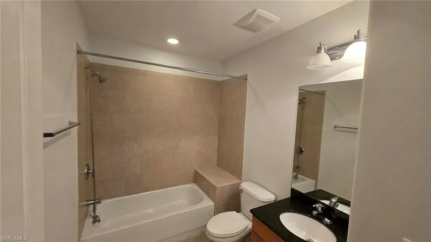 Full bathroom featuring tiled shower / bath combo, toilet, and vanity