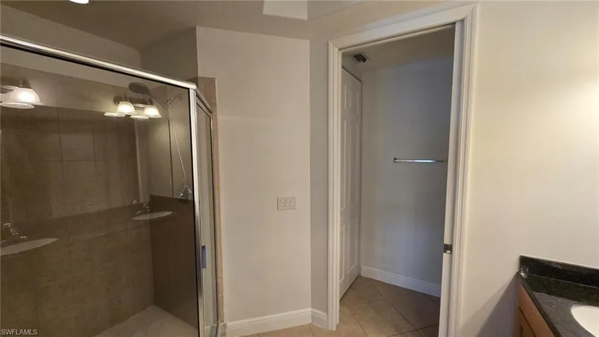 Bathroom featuring tile patterned floors, vanity, and a shower with door