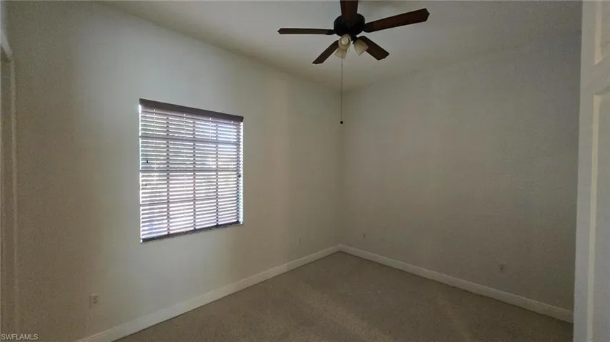 Carpeted empty room featuring ceiling fan