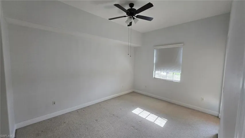 Unfurnished room with light colored carpet and ceiling fan
