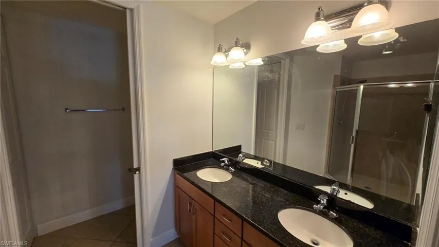 Bathroom featuring tile patterned floors, vanity, and walk in shower