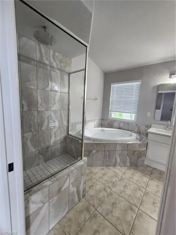 Bathroom featuring tile flooring, a textured ceiling, vanity, and plus walk in shower