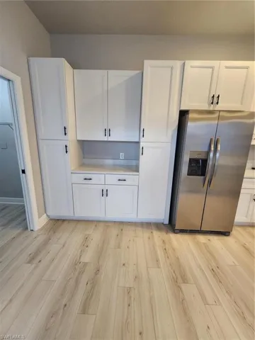 Kitchen with refrigerator, white cabinetry, and light wood-type flooring