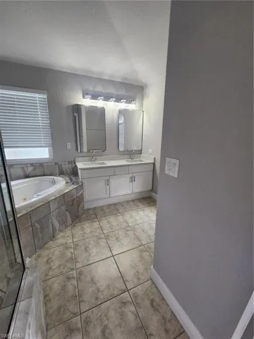 Bathroom with tile floors, double sink vanity, and plus walk in shower