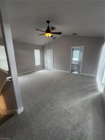 Carpeted spare room featuring lofted ceiling and ceiling fan