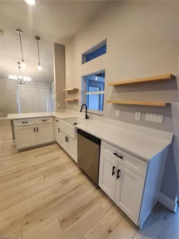 Kitchen with white cabinets, light hardwood / wood-style flooring, kitchen peninsula, dishwasher, and sink