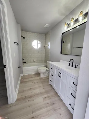 Full bathroom with tiled shower / bath combo, vanity, and toilet