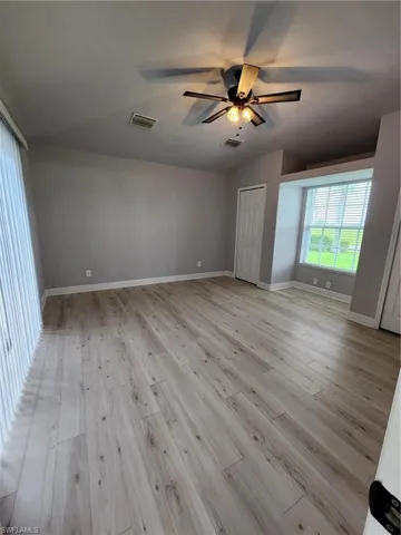 Unfurnished room with lofted ceiling, ceiling fan, and light hardwood / wood-style flooring