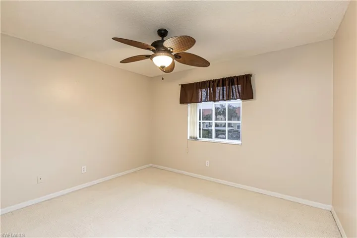 Carpeted empty room with ceiling fan and a textured ceiling