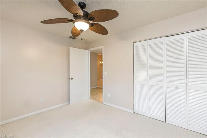 Unfurnished bedroom featuring ceiling fan, light colored carpet, a textured ceiling, and a closet