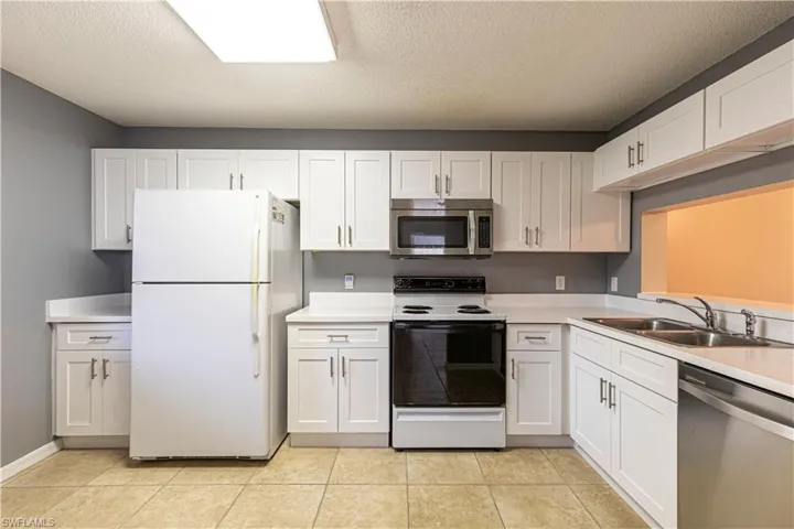 Kitchen with sink, white cabinets, a textured ceiling, and appliances with stainless steel finishes