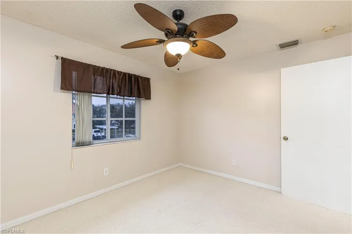Unfurnished room with a textured ceiling, light colored carpet, and ceiling fan