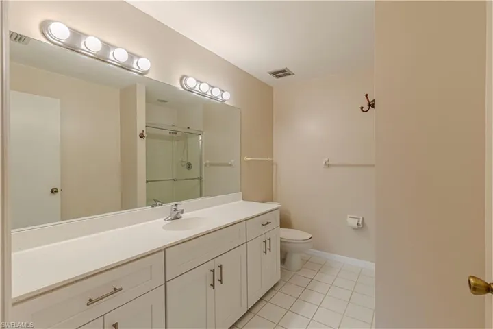 Bathroom featuring tile patterned floors, an enclosed shower, vanity, and toilet