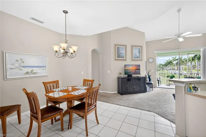 Dining area featuring a decorative chandelier, tile flooring, and an arched entryway