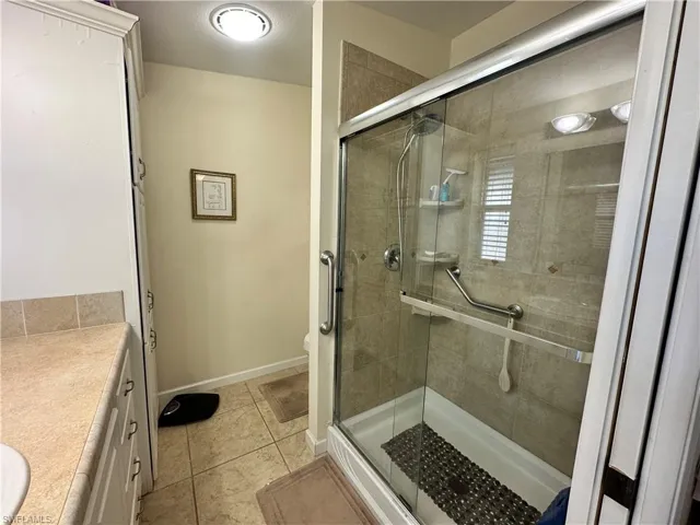 Full bathroom with vanity, a shower stall, and light tile patterned floors
