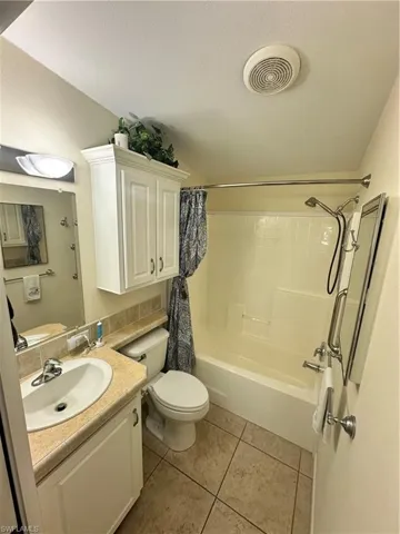 Full bath with vanity, shower / tub combo with curtain, light tile patterned floors, and a textured ceiling