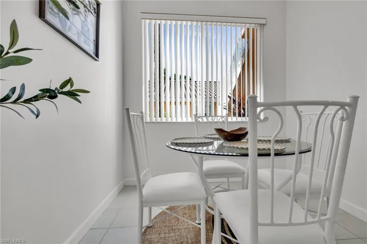 White vertical blinds cover a window in this room featuring light-colored tile flooring and white baseboards