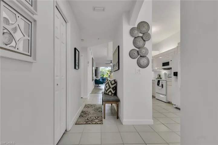 Bright interior hallway with white walls and light-toned tile flooring