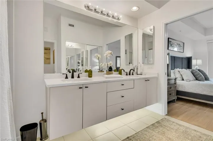 Dual vanity with white countertop and integrated sinks, matte black fixtures, and extensive mirror space