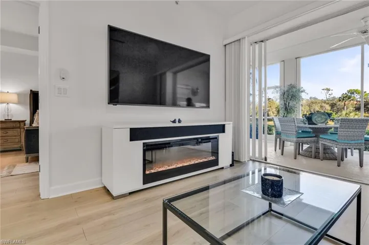 Bright interior with wood-finish flooring, a wall-mounted display, and an integrated linear fireplace