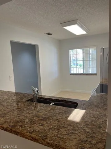 Kitchen with a textured ceiling, refrigerator, sink, and range